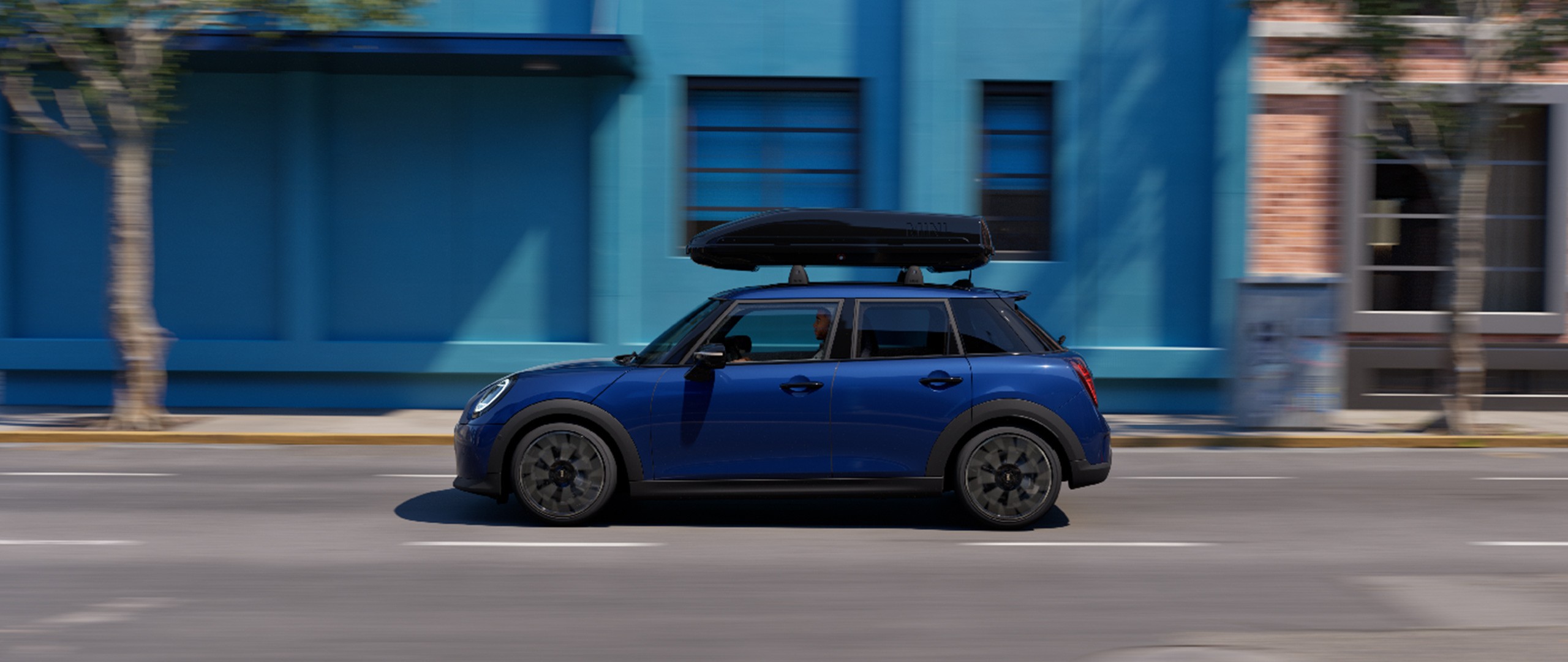 Front view of MINI Aceman in Indigo Sunset Blue with MINI Roof Bike Rack, carrying a mountain bike and MINI Roof Box 320.